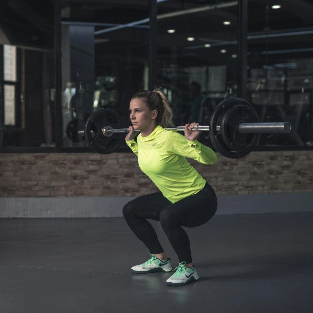 Woman over 40 performing a barbell back squat, demonstrating safe beginner strength-training form