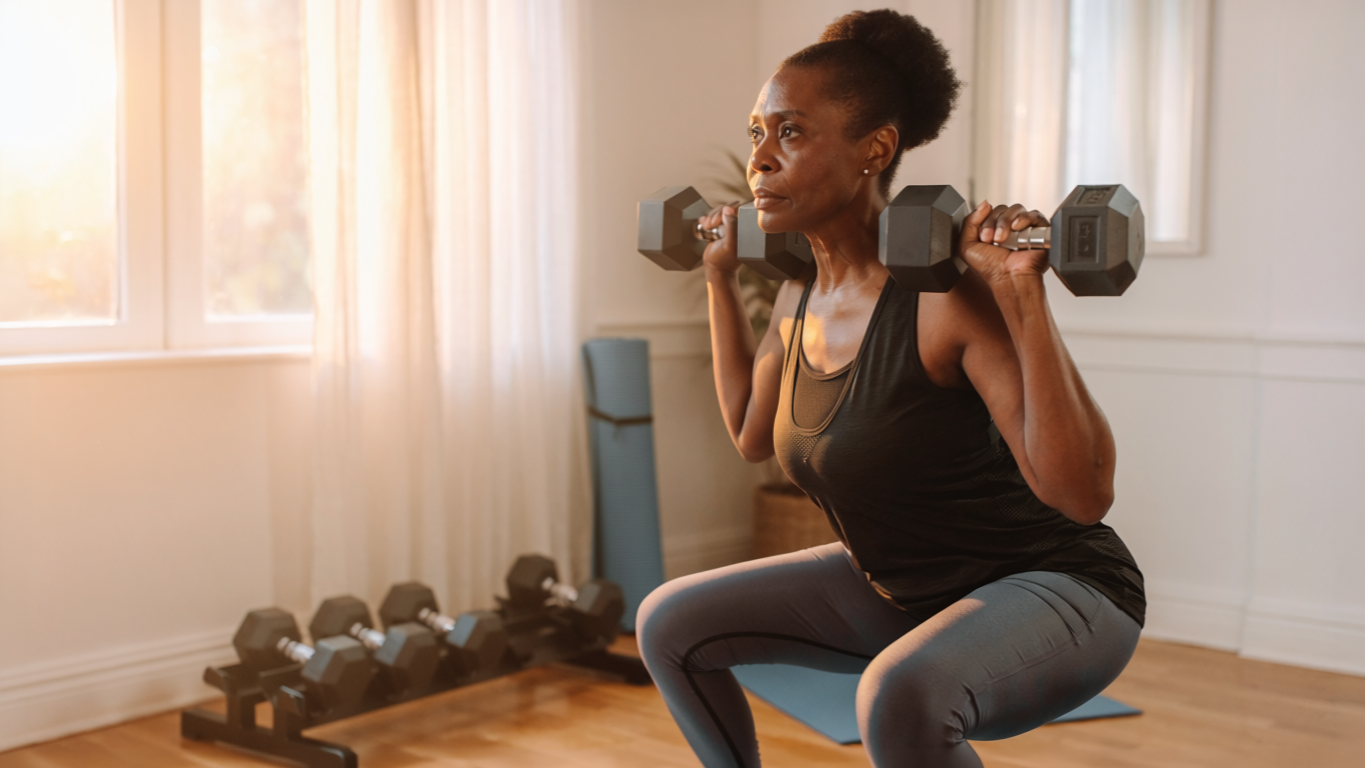 Woman in her late 40s performing a dumbbell squat in a bright home gym